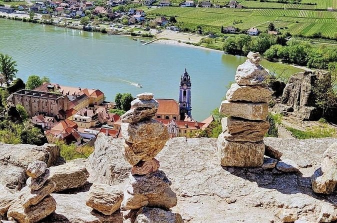Stone cairns on a rocky outlook, with Dürnstein's blue tower and the Danube below