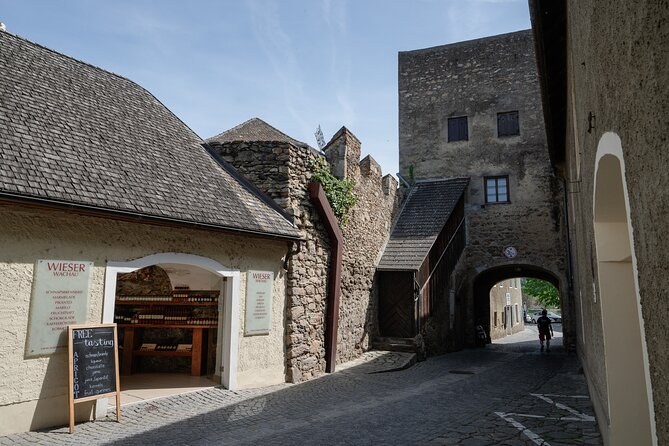 An old stone town gate and tower beside a shop front with a chalkboard