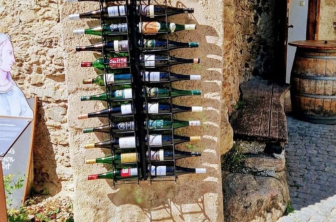 Wine bottles racked on an old stone wall beside a barrel